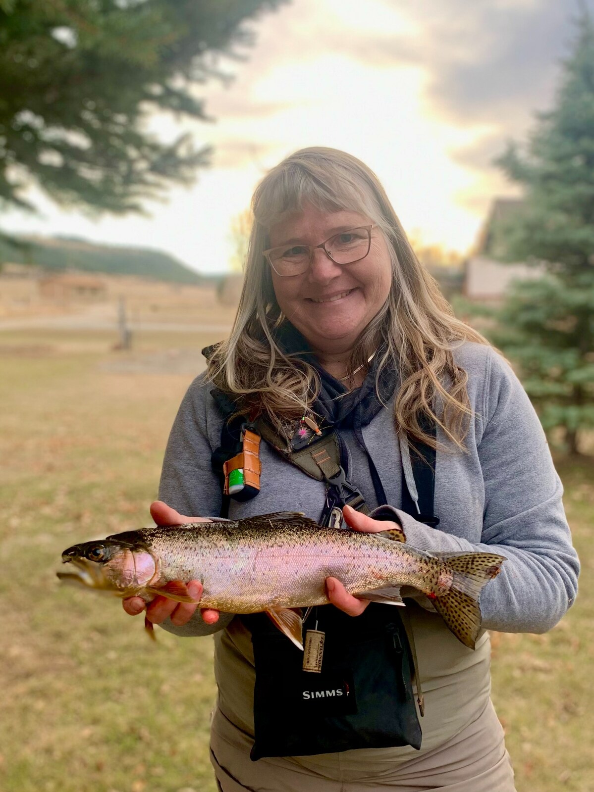 Nancy Gerbasi, founder of 1 Addicted Hobbyist LLC, holding a trout outdoors